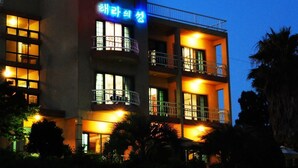 A multi-story hotel with illuminated windows and balconies. - Hera's Castle (Seogwipo)