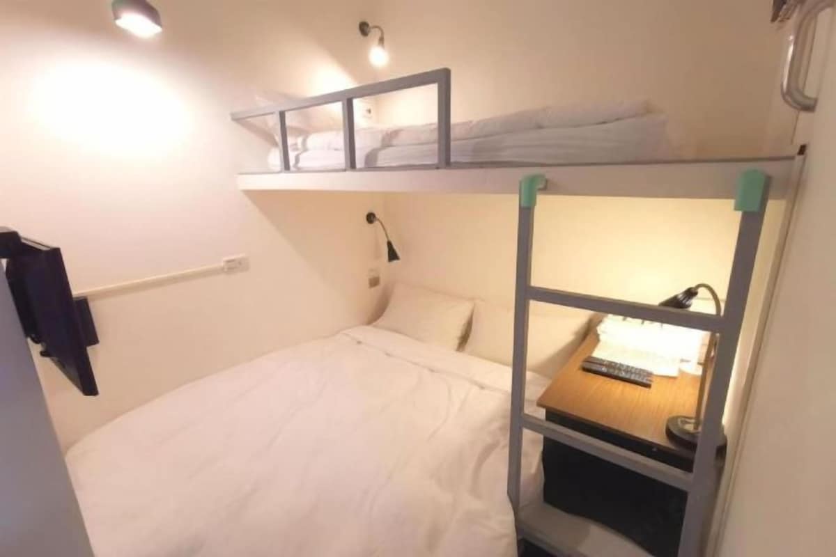 A bunk bed room with a desk and a lamp.