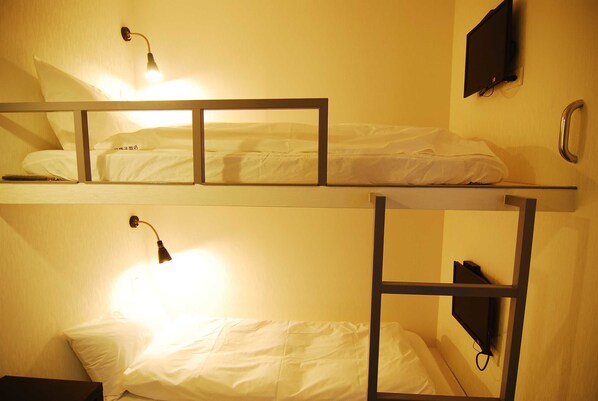 Quarto com beliche e duas camas, cada uma com abajur.