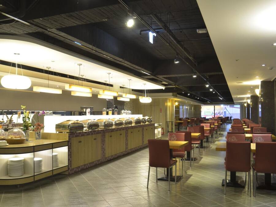 A modern restaurant with a buffet counter, multiple dining tables, and chairs.