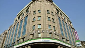 A hotel with a curved facade, multiple windows, and a green and white FamilyMart sign at the ground level.