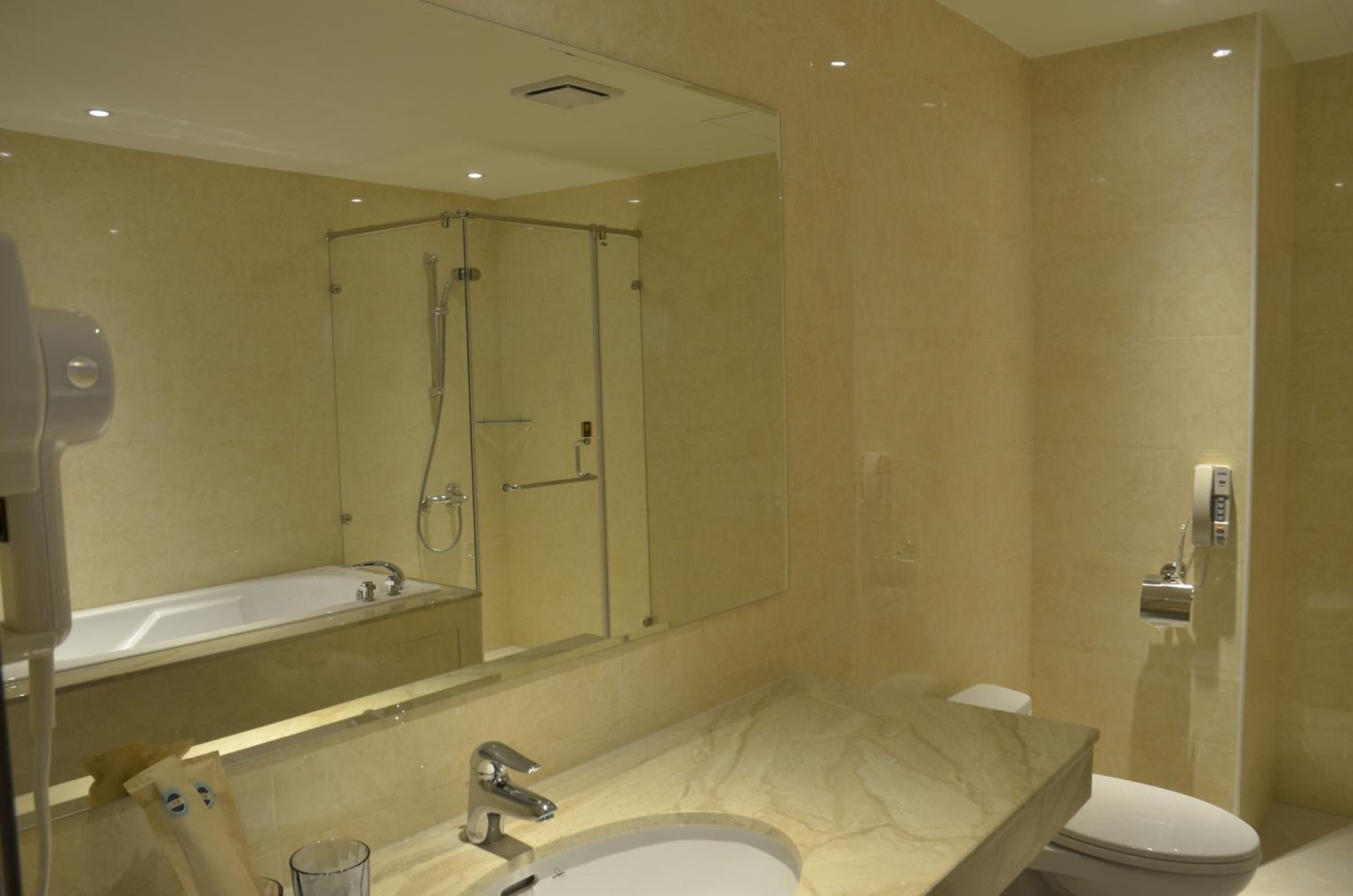 Une salle de bain moderne avec un grand miroir, une baignoire, une douche et des toilettes.