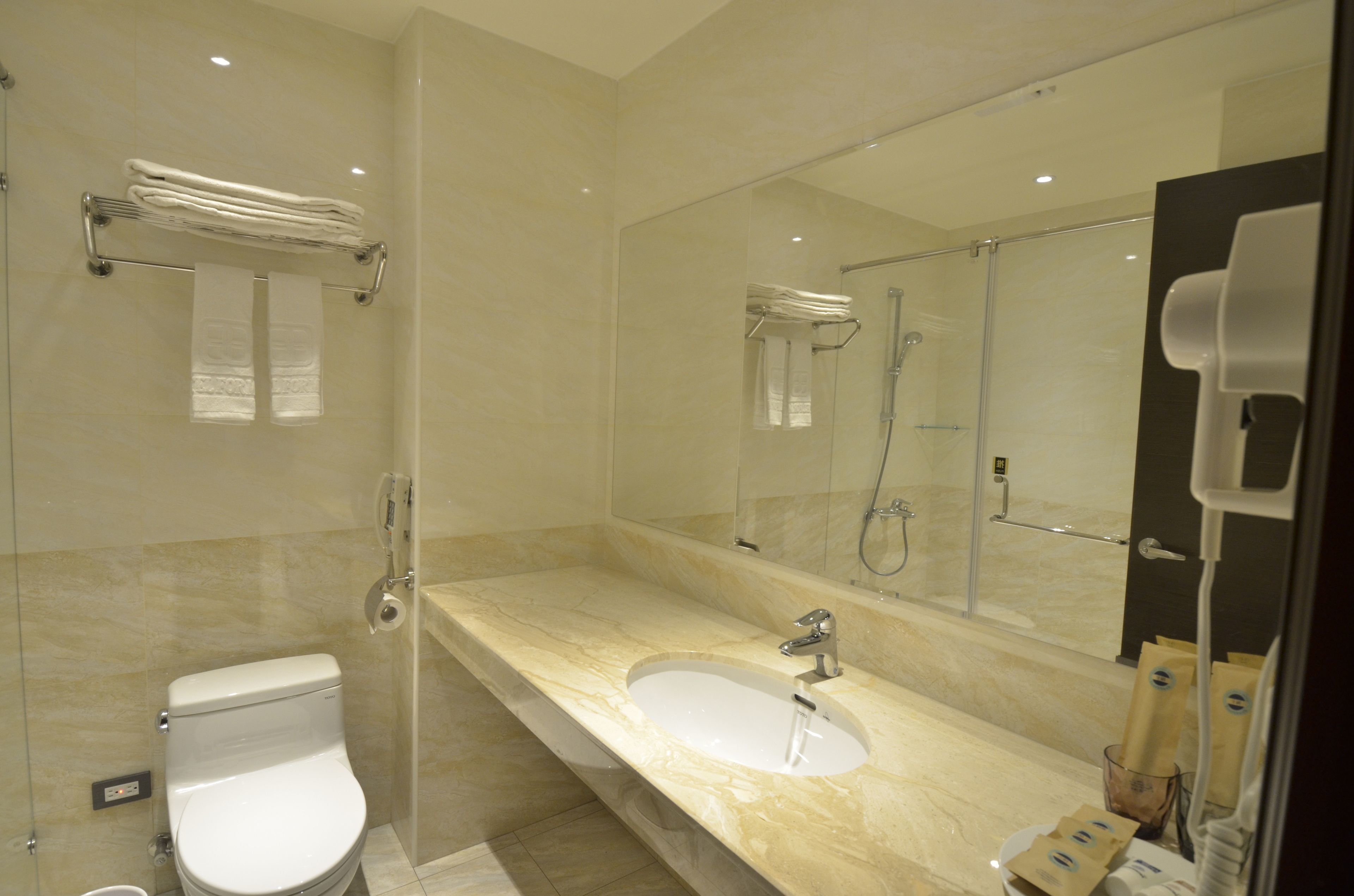 A modern bathroom with a glass-enclosed shower, a marble sink, and a large mirror.