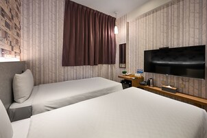 Habitación de hotel con dos camas, un televisor, un escritorio con teléfono y un espejo.