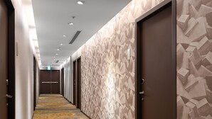 A hotel hallway with patterned walls, a carpeted floor, and doors leading to rooms. - Le Room Hotel Taoyuan (Taoyuan City)
