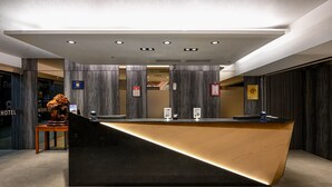 A modern reception desk with a black and wooden finish, a digital screen, and a plaque. - Le Room Hotel Taoyuan (Taoyuan City)