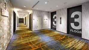 A hotel corridor with a patterned carpet, doors labeled with floor numbers, and a fire alarm panel. - Le Room Hotel Taoyuan (Taoyuan City)