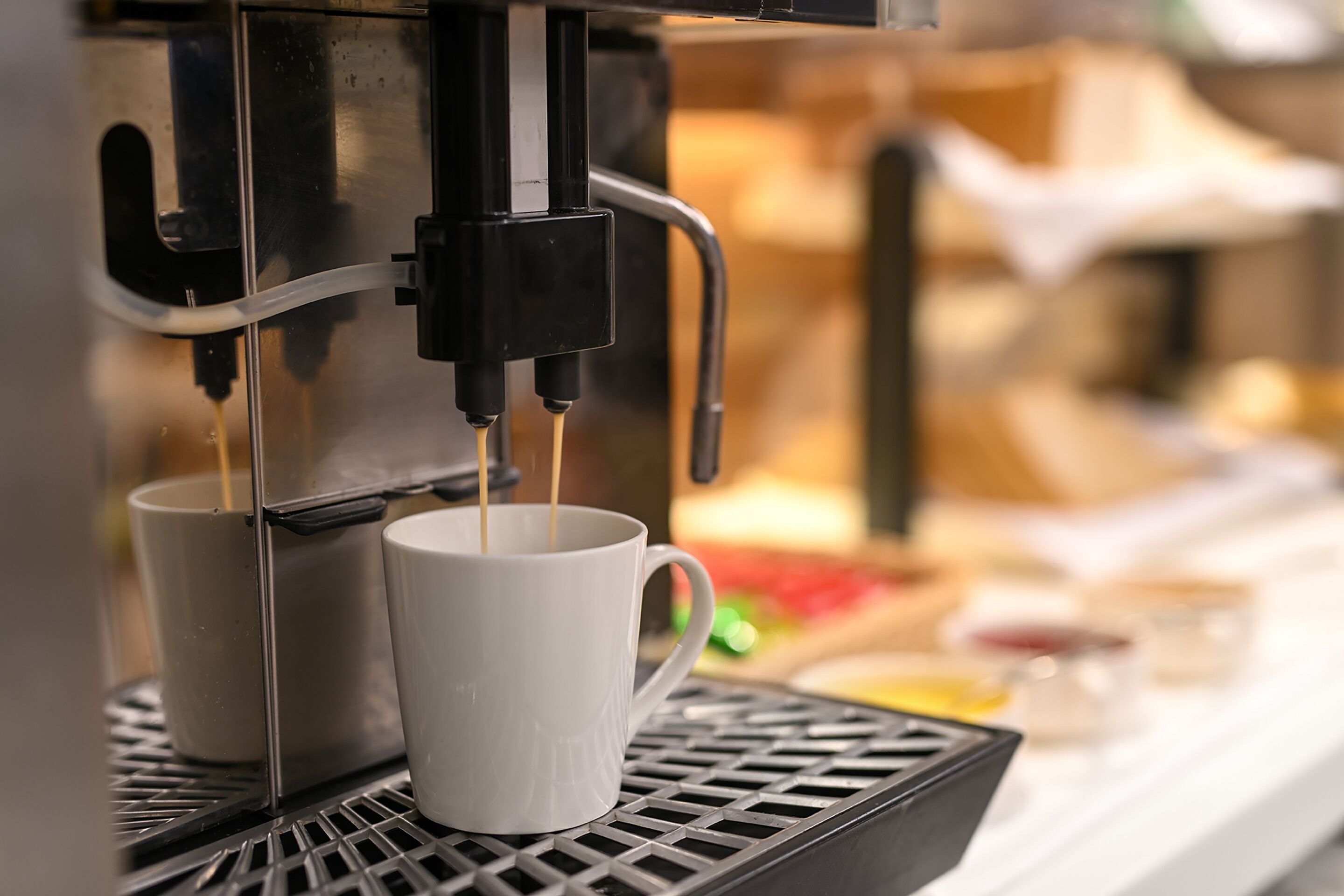 Une machine à café verse du café dans deux tasses blanches.