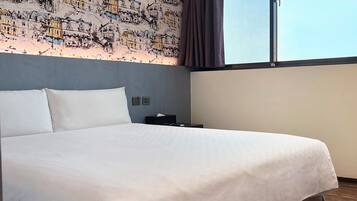 A hotel room with a large bed, a nightstand, a power outlet, and a window with curtains.