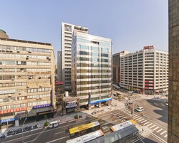 Een meerlaags gebouw met een moderne glazen gevel, meerdere airconditioners en een zichtbaar hotelbord.