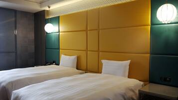 Une chambre d’hôtel avec deux lits, une tête de lit à motifs et une table de chevet avec une lampe.