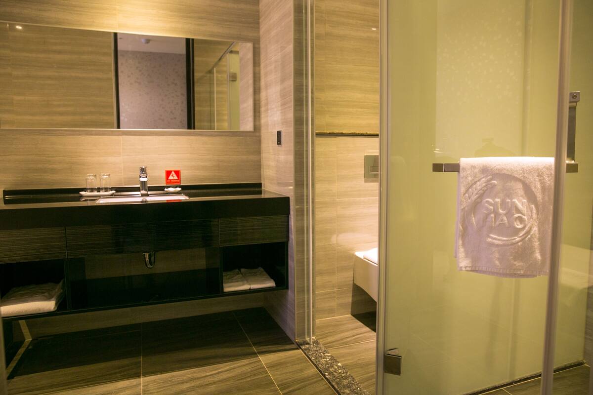 Une salle de bain moderne avec une douche à parois de verre, un meuble-lavabo avec un miroir et une serviette accrochée à la porte.