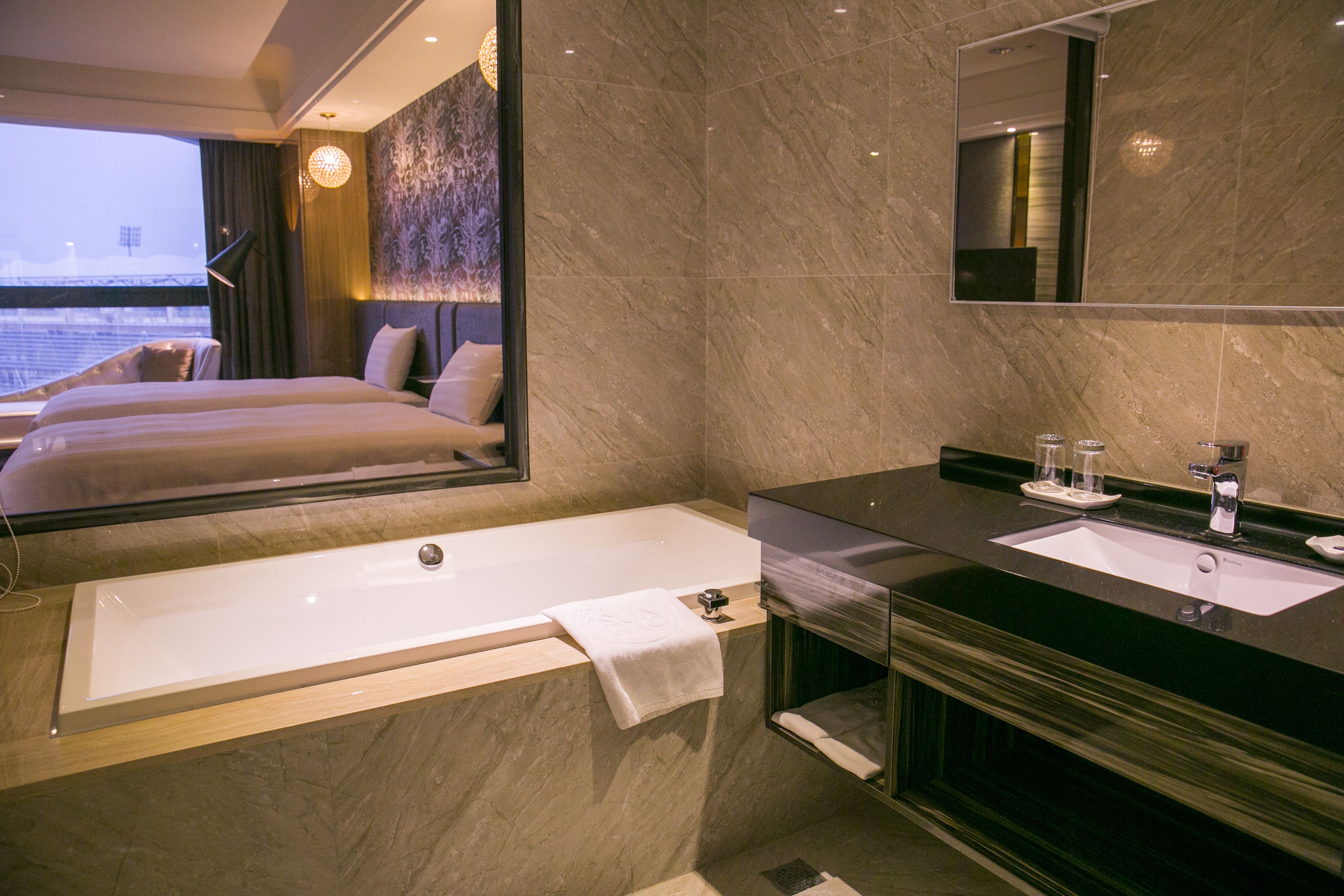 A modern hotel bathroom with a large bathtub, a sink, and a mirror.