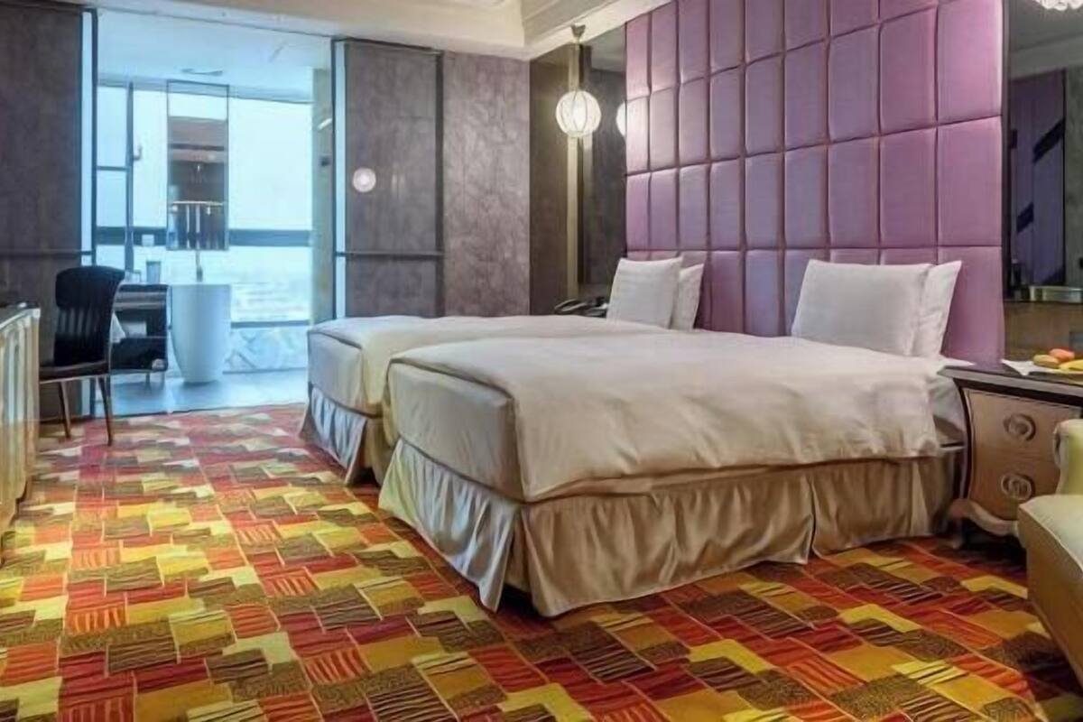 Une chambre d’hôtel avec un grand lit, un bureau et une vue sur l’extérieur, visible à travers une porte vitrée.