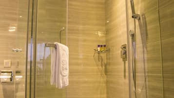 A modern glass-enclosed shower with a handheld showerhead and a wall-mounted faucet.