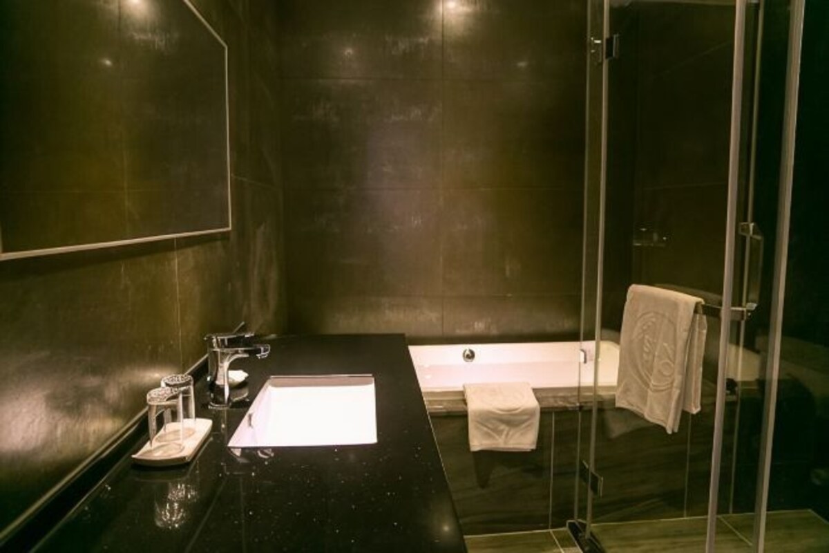 Une salle de bain moderne avec un plan de toilette noir, une douche en verre et une baignoire blanche.