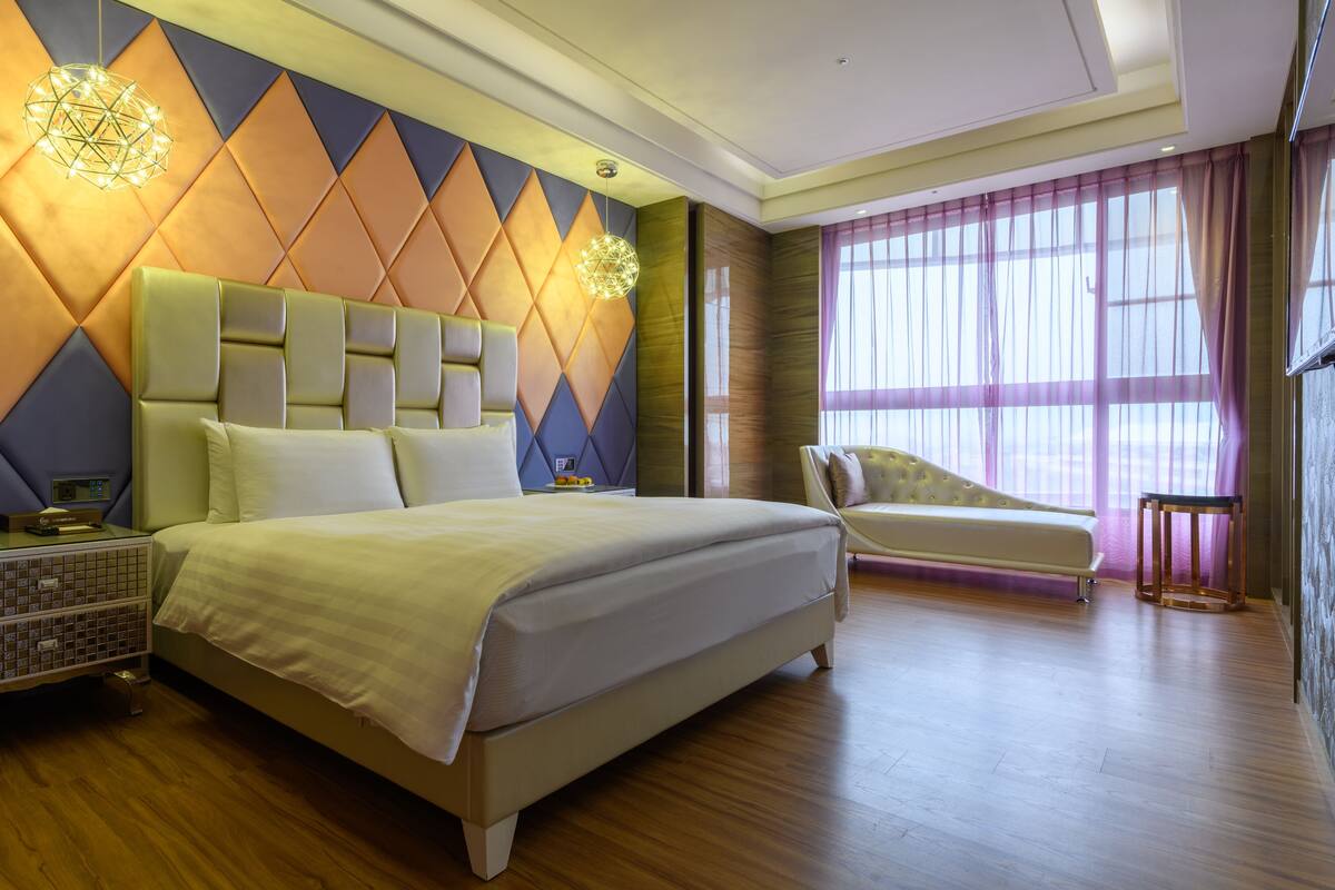 Une chambre d’hôtel moderne, dotée d’un grand lit, d’un canapé et d’une table de chevet.