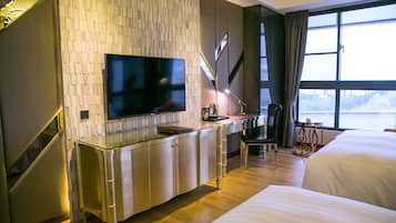 Une chambre d’hôtel dotée d’un grand téléviseur à écran plat fixé au mur, d’un bureau avec une chaise, d’un lit et offrant une vue sur l’extérieur grâce à une grande fenêtre.