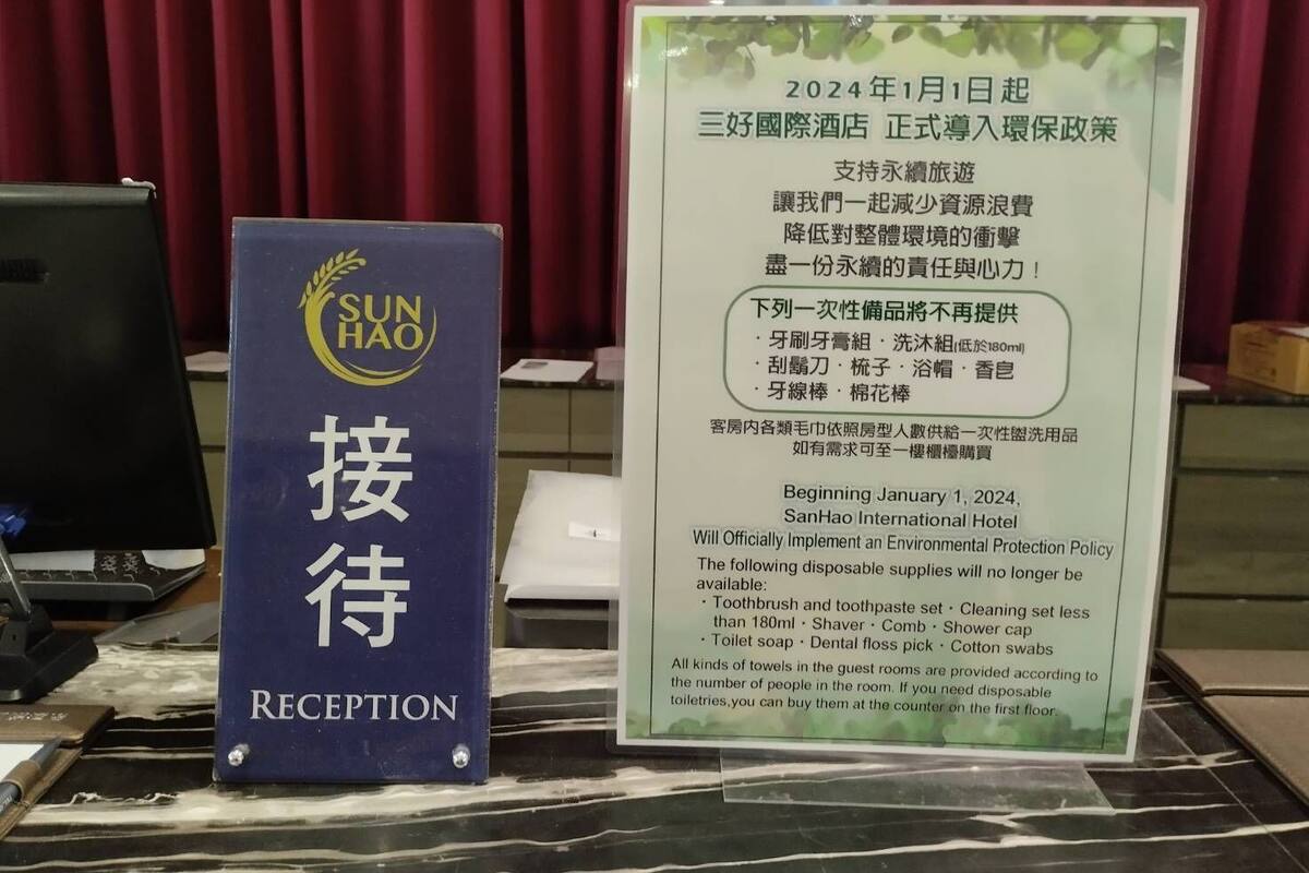 Un comptoir d’accueil avec une affiche indiquant la politique de protection de l’environnement de l’hôtel SanHao International, en vigueur à partir du 1er janvier 2024.