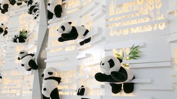 A wall with multiple panda sculptures and small plants.