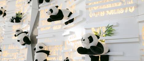 A wall with multiple panda sculptures and small plants.