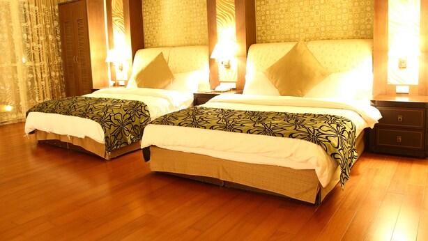 A hotel room with two beds, wooden flooring, and patterned wallpaper. - Constellation Coast B&B (Hualien City)