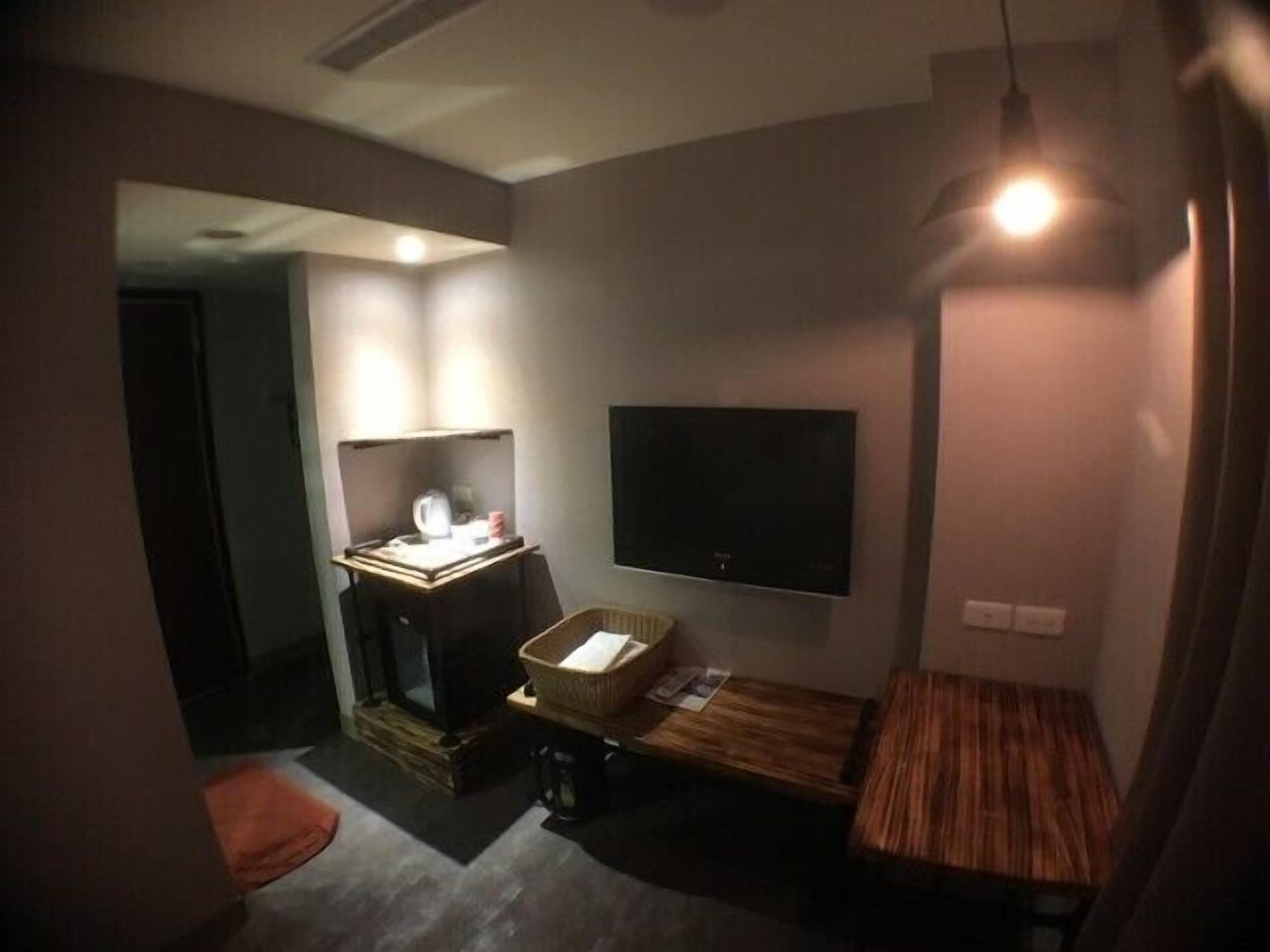 A compact room with a flat-screen TV mounted on the wall, a small wooden table, and a seating area with a bench.