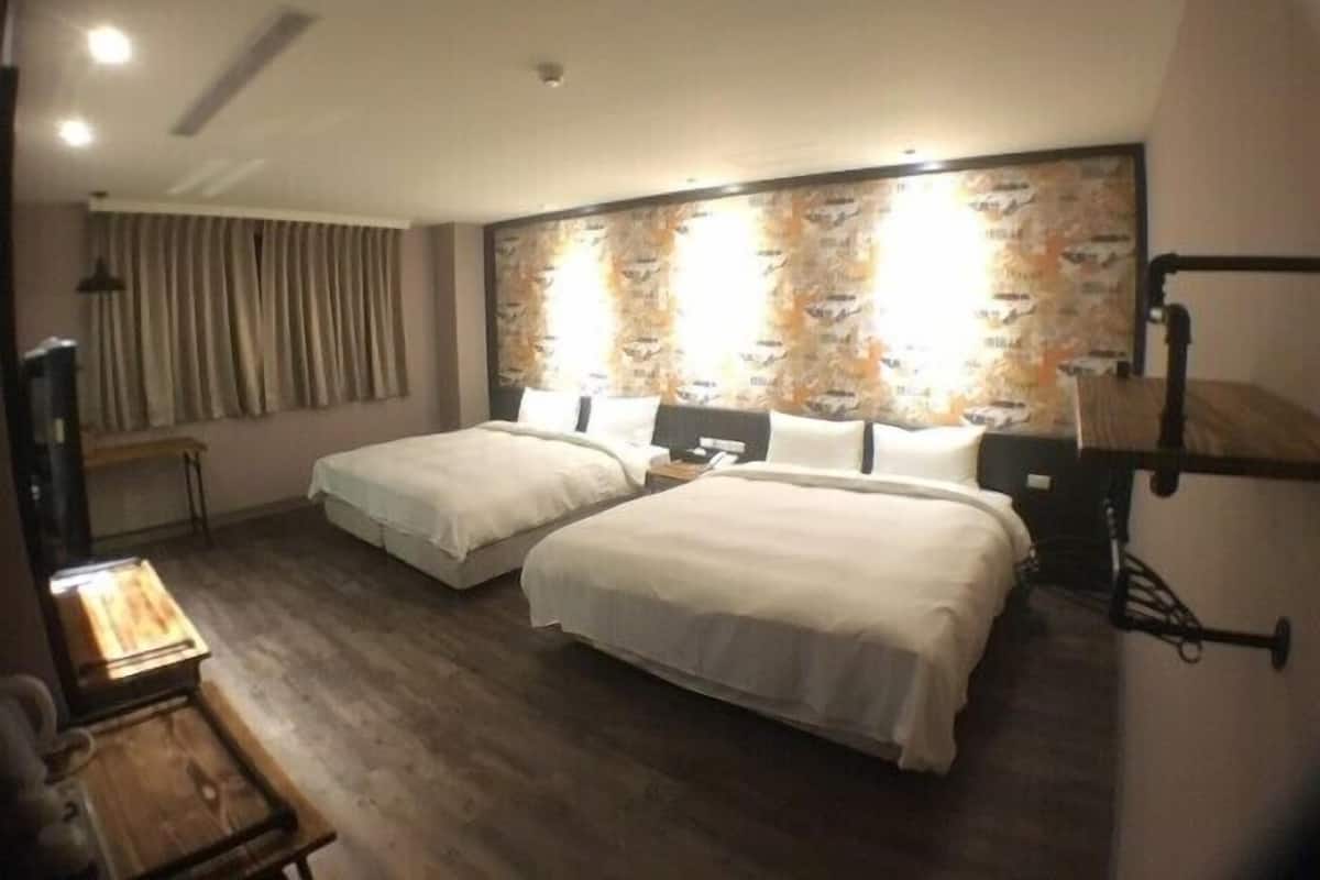 Habitación de hotel con dos camas, un escritorio de madera, un mapa en la pared y una lámpara en el techo.