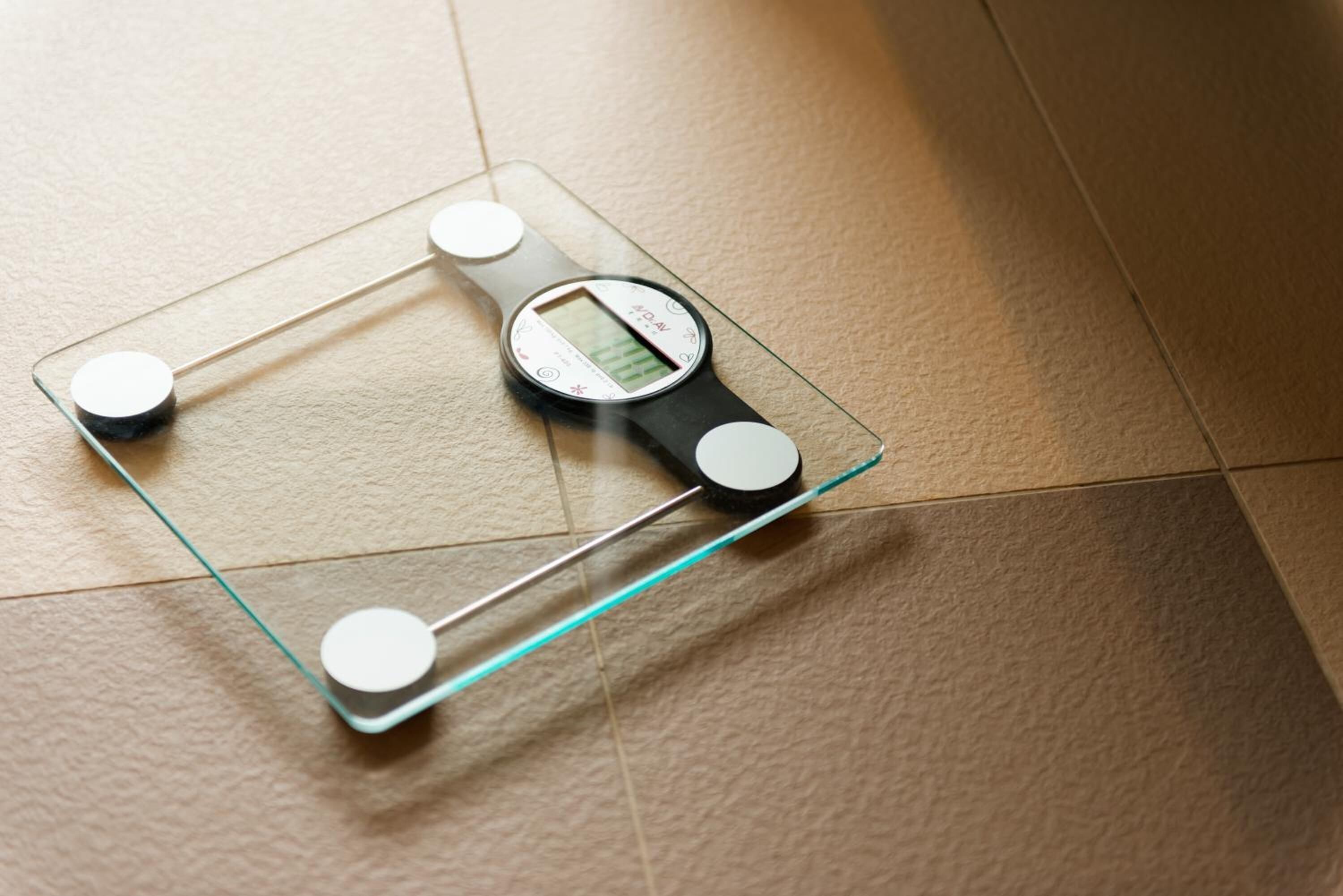 A bathroom scale with a digital display on a tiled floor.