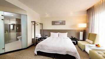 Relax in a spacious room with a large bed, separate seating area, and glass-enclosed shower.