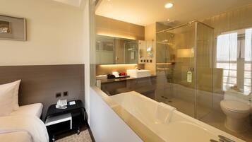 A modern bathroom with a glass-enclosed shower, a large bathtub, and a separate toilet.