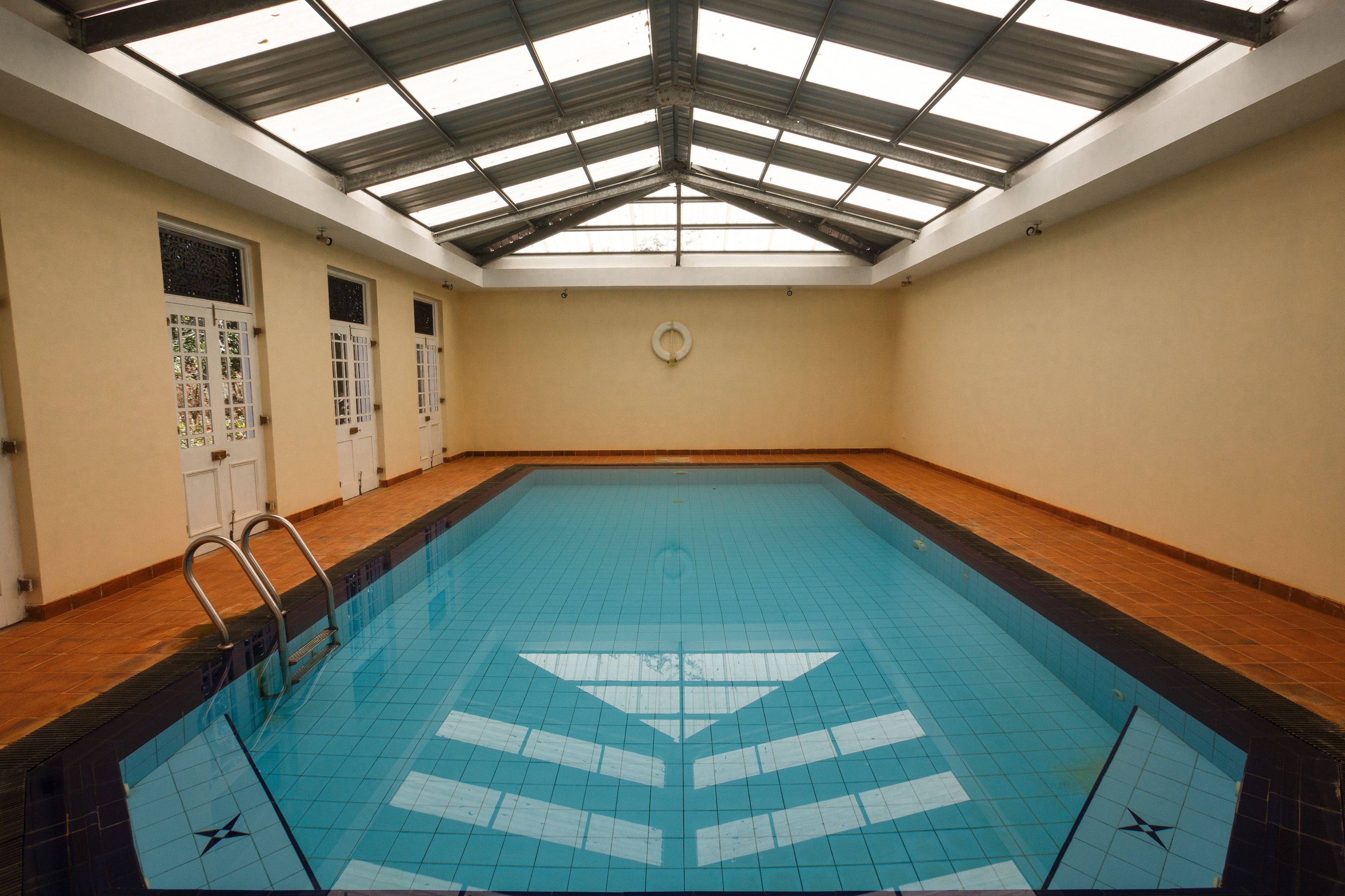 Ein Hallenbad mit Fliesenboden, Metallveranda und Holzboden rund um den Pool.