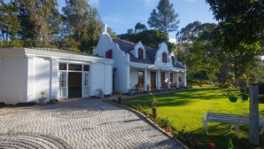 Un edificio de estilo colonial blanco con un camino de adoquines y un césped cuidado.
