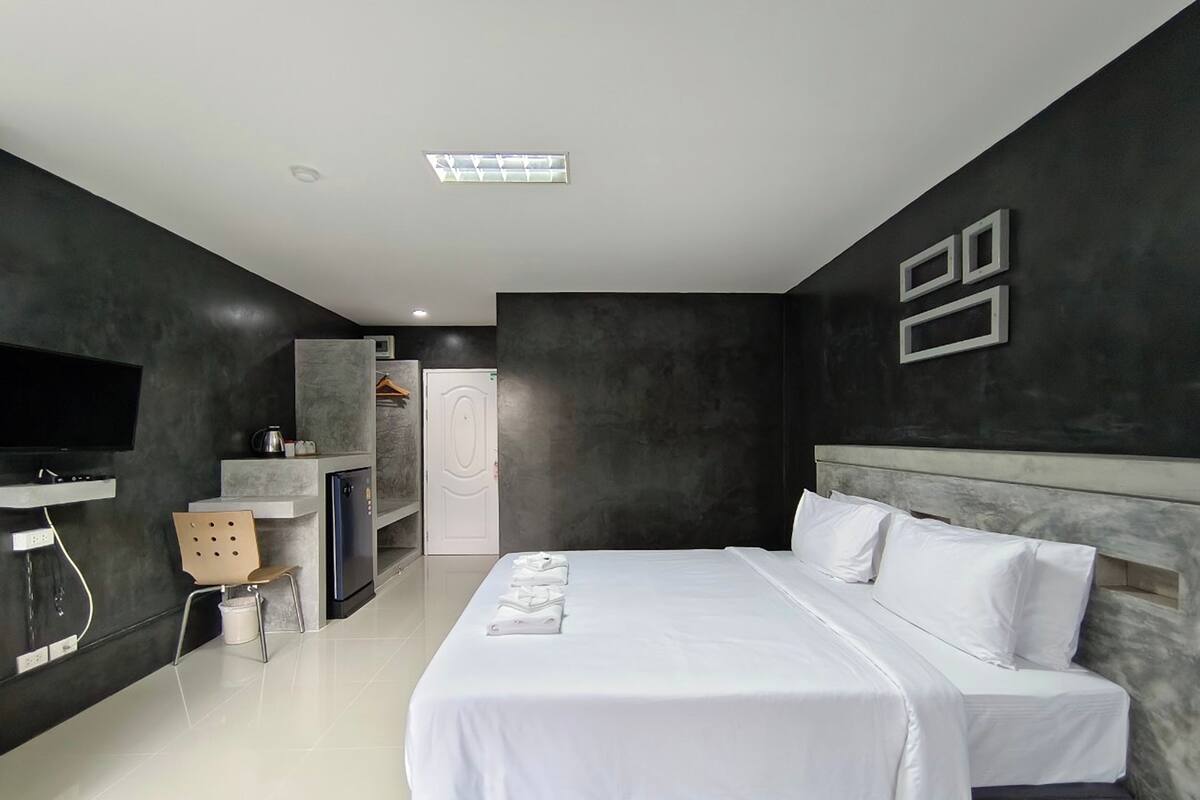 Une chambre d’hôtel moderne dotée d’un grand lit, d’une télévision à écran plat, d’une armoire et d’un petit coin salon.