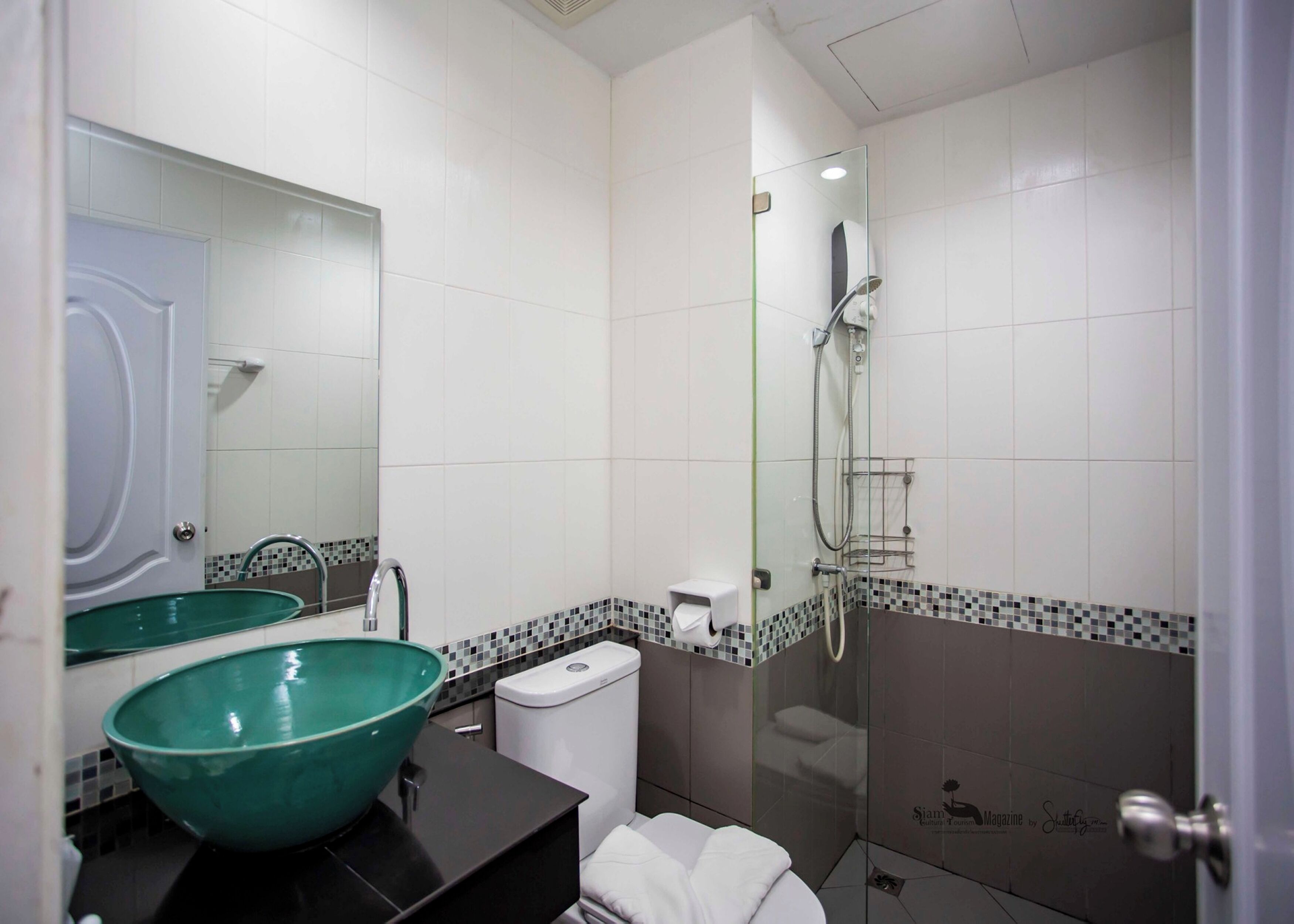 A modern bathroom with a large green sink, a glass shower enclosure, and a white toilet.