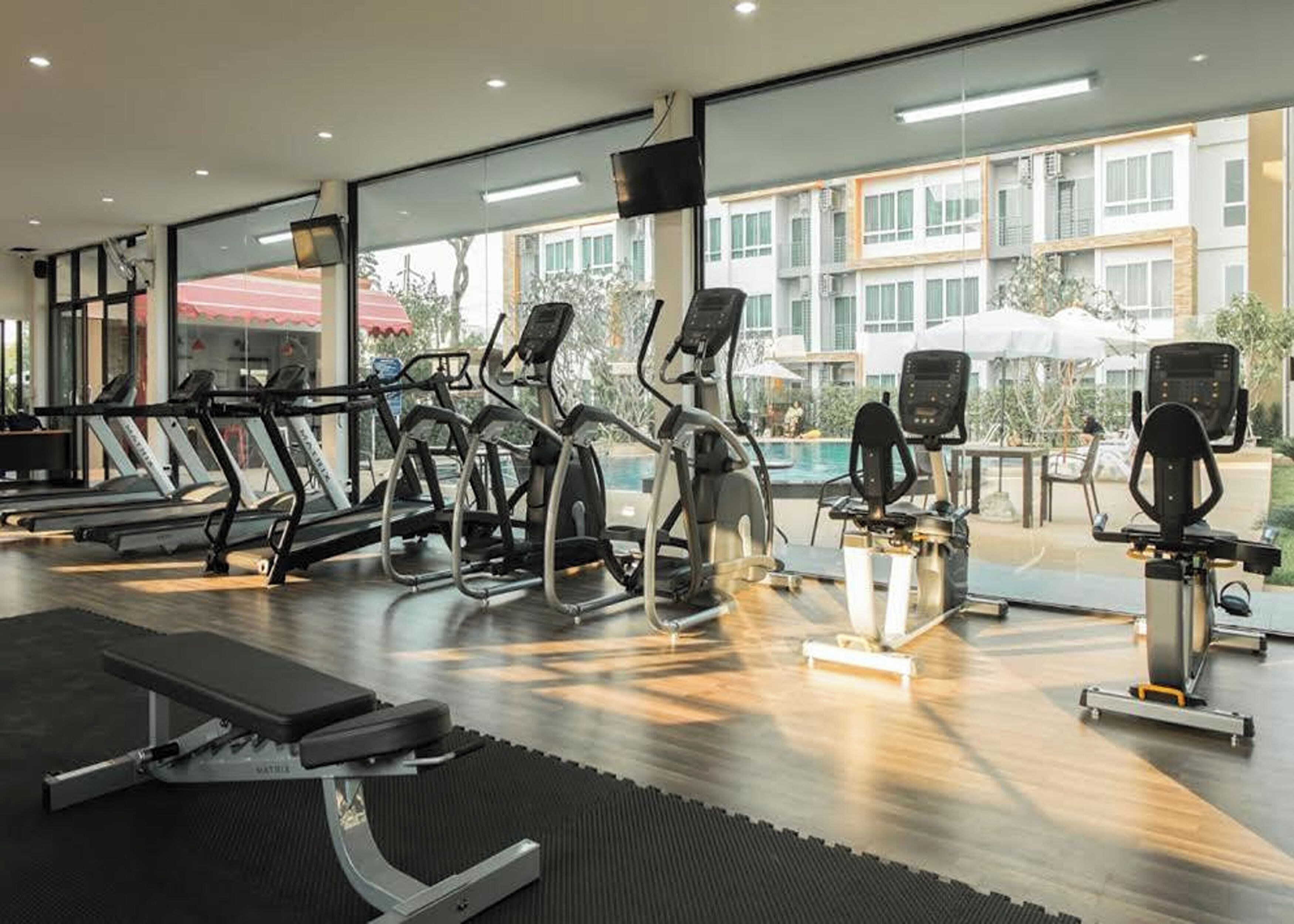 Un gimnasio con cintas de correr, elípticas y una banca.