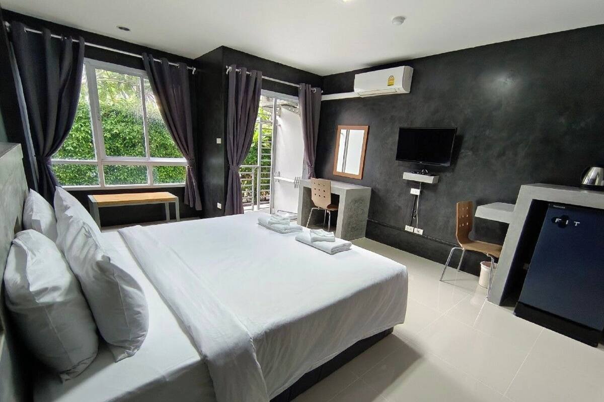 Une chambre d’hôtel moderne équipée d’un grand lit, d’un bureau, d’une chaise, d’une télévision et d’un appareil de climatisation.
