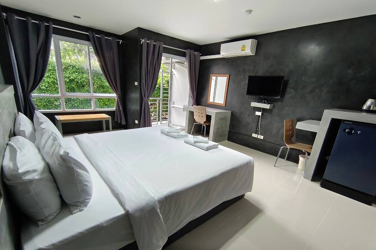 Une chambre d’hôtel moderne équipée d’un grand lit, d’un bureau, d’une chaise, d’une télévision et d’un appareil de climatisation.