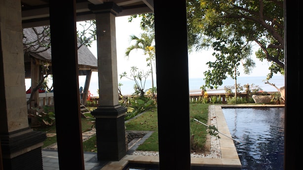 A pool area with a view of the sea, surrounded by greenery and architectural columns. - Joglo on the Beach (Banjar)
