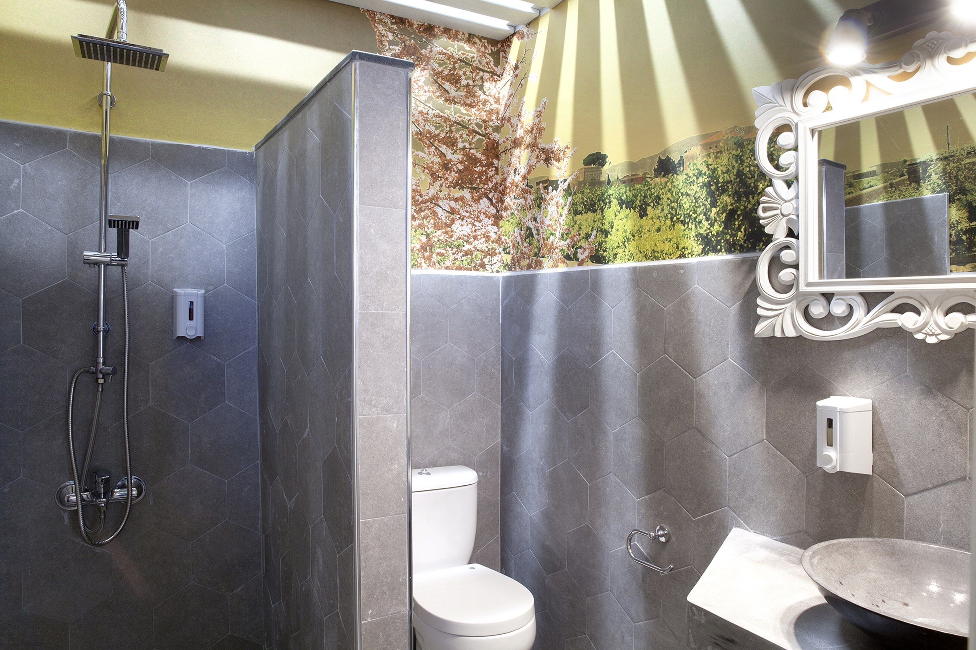 A modern bathroom with a shower, toilet, and sink, featuring hexagonal tiles and a decorative mirror.