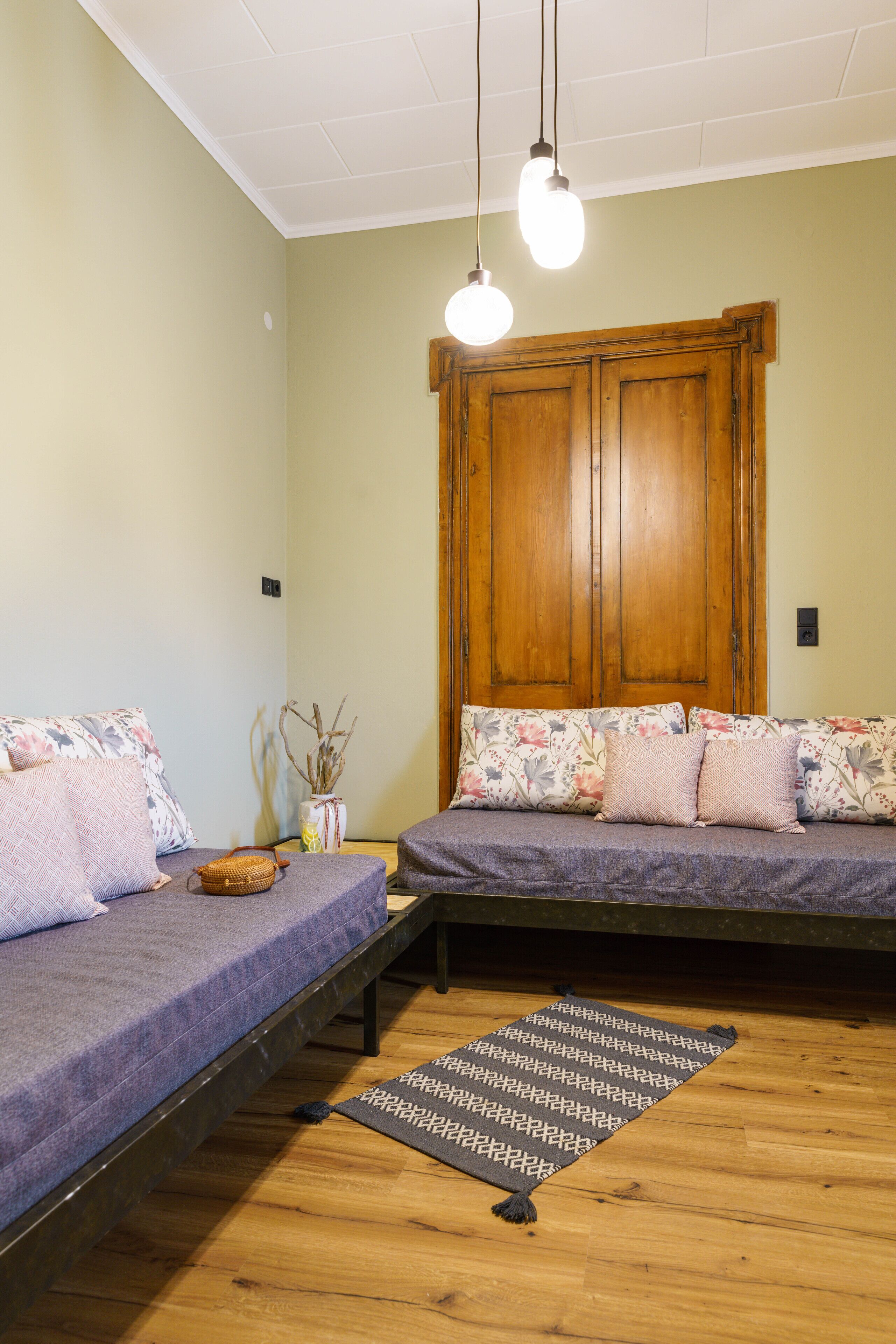 Une chambre avec deux lits, une armoire en bois et un luminaire suspendu.