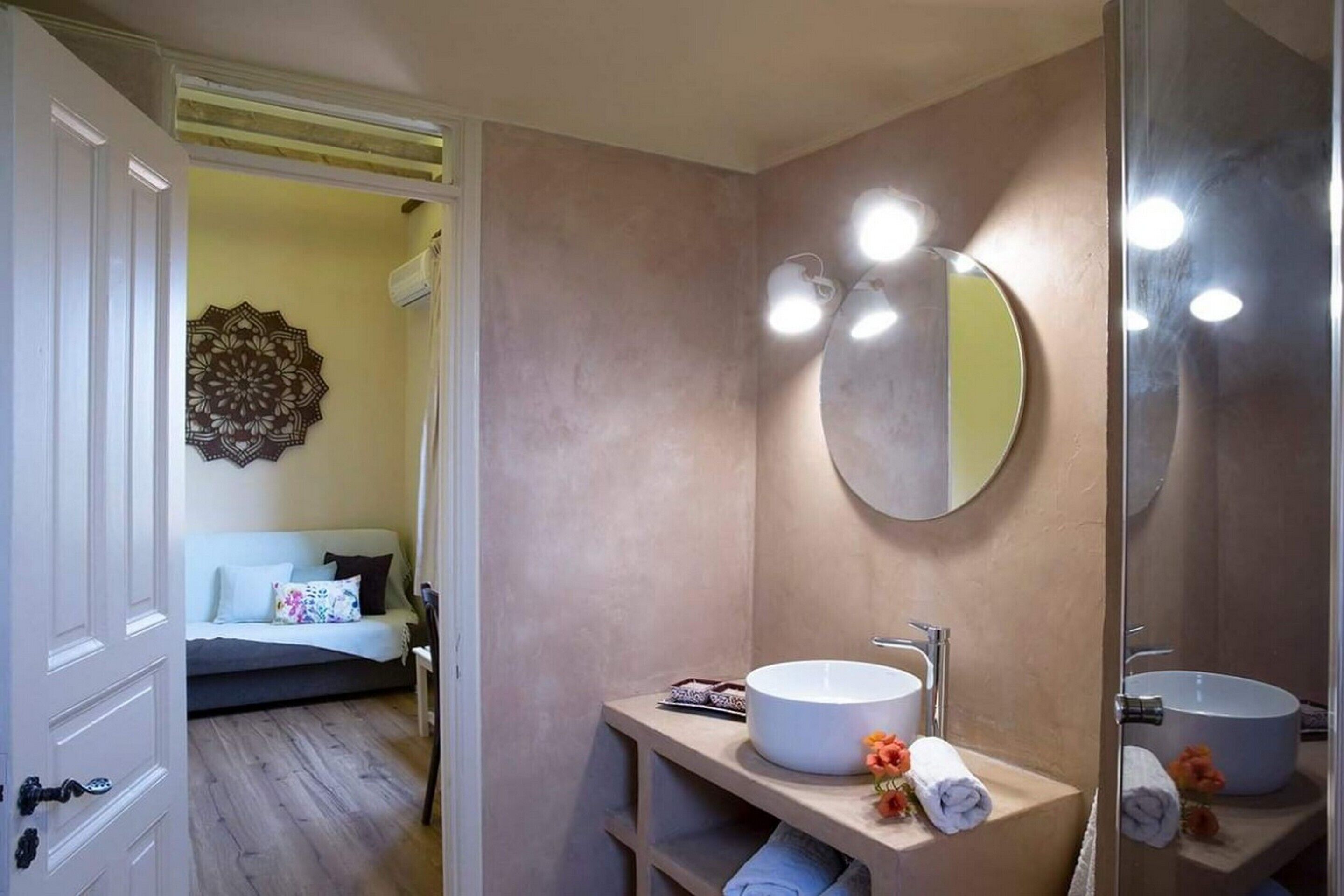 A bathroom with a round mirror, two sinks, and a decorative wall piece.