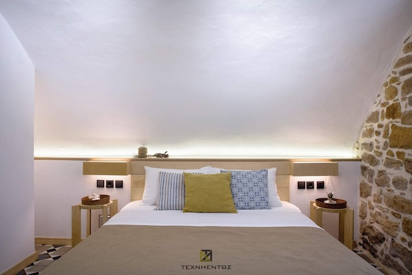 Una habitación de hotel con una cama, mesitas de noche y una pared de piedra.