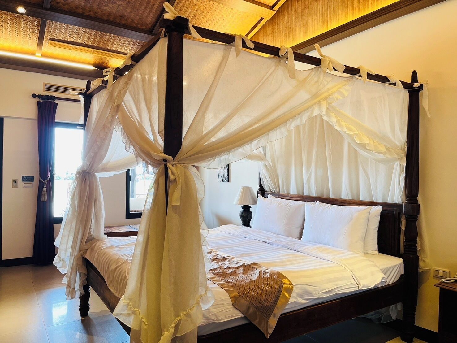 A four-poster canopy bed with white linens and a decorative throw pillow.