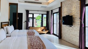 A modern hotel room with a large bed, a flat-screen TV mounted on a stone wall, and a view of the outdoors through large windows. - Pangola B&B (Hengchun)