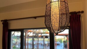 A room with a large window, a hanging light fixture, and a view of the outdoors. - Pangola B&B (Hengchun)