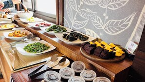 A buffet table with various dishes, a book, and disposable cups. - Pangola B&B (Hengchun)