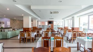 A spacious dining area with multiple tables and chairs, a buffet setup, and large windows providing natural light. - Relax Hotel (Phnom Penh)