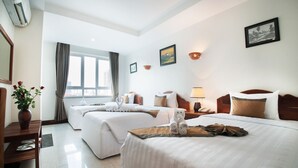 A hotel room with two beds, a wooden nightstand, a lamp, a vase with flowers, and a window with curtains. - Relax Hotel (Phnom Penh)
