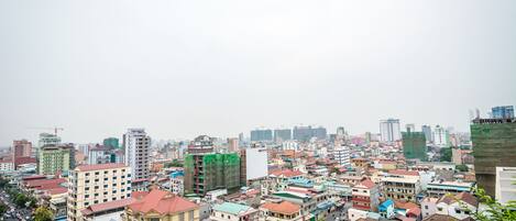 A cityscape with a mix of residential and commercial buildings, including a prominent yellow building with a red roof in the foreground.